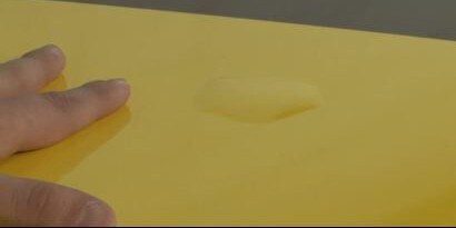A hand touches a yellow graphic wrap.
