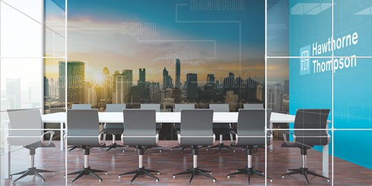 An office conference room has graphic wraps with a cityscape and logo on another wall.
