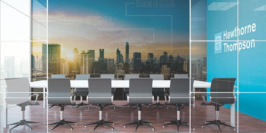 An office conference room has graphic wraps with a cityscape and logo on another wall.
