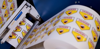 Image of Hazard Warning labels being wound onto a roll from a printer
