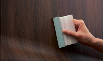 Someone applying a 3M DI-NOC wood grain architectural film

