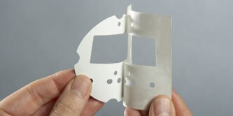 Hands holding a custom-cut gasket for an appliance
