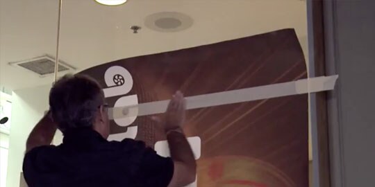 A worker installs a window film on a pane of glass.

