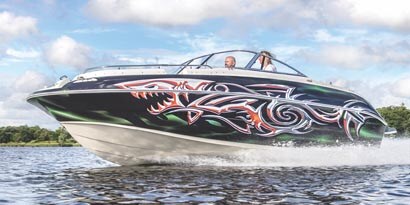 A speedboat running on a lake wrapped in a dark blue color with a tribal white shark graphic using 3M envision gloss wrap overlaminate 8548G.
