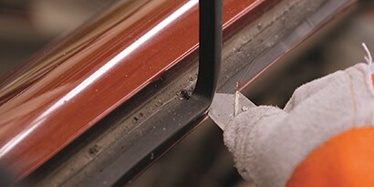 cutting old seam sealer to prepare window opening for new glass
