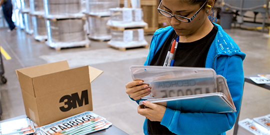 a worker sorts new licence plates made with 3M materials
