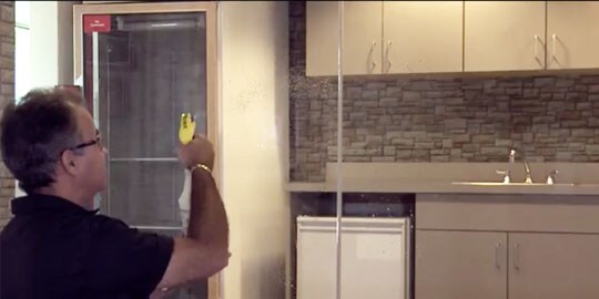 A man preps a window for installation of a glass film.
