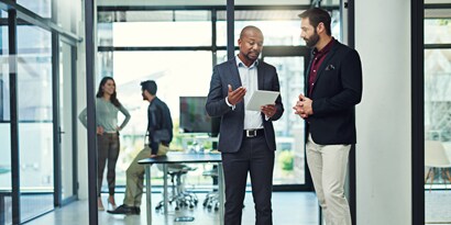 Man consulting tablet and explaining something to other man