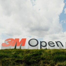 A medium shot of the 3M Open logo situated as large individual letters on grass under a cloudy sky.