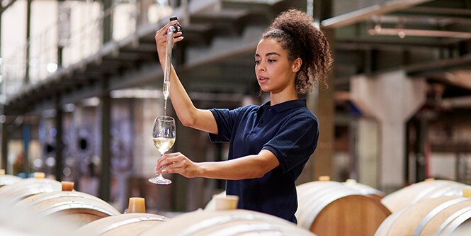 image of woman pouring wine sample into a wine glass
