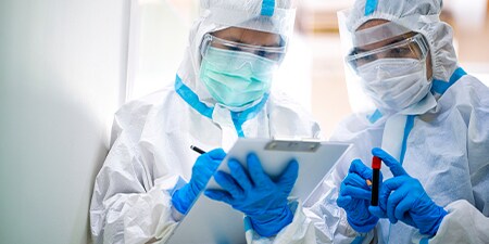 Image of a healthcare professional in protective clothing working in a lab facility setting
