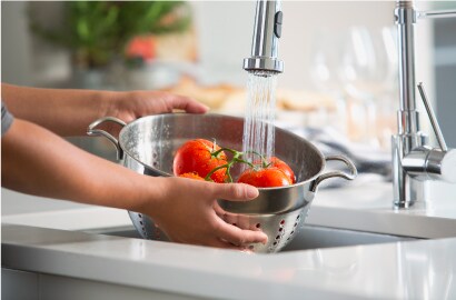 Woman rinsing food with quality water from residential tap
