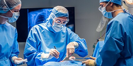 Image of four healthcare professionals working together in a surgery room setting
