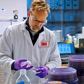 A male scientist in 3M lab coat examines a 3M product