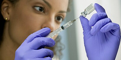 A women drawing vaccine out of a vial.  
