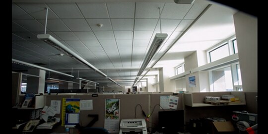 A room with cubicles and a light in the background
