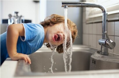 Boy drinking water from a residential tap
