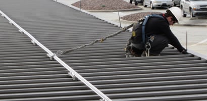 Worker on roof connected to permanently mounted rigid rail system
