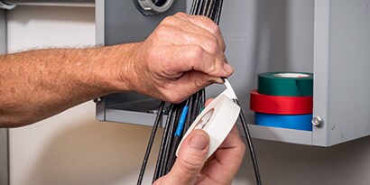 man using colored tape at electrical box
