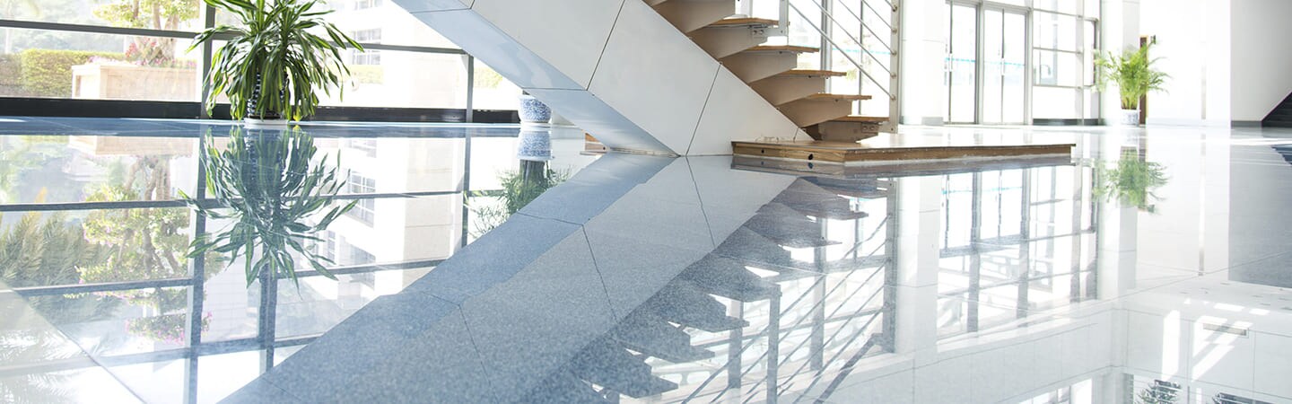 Image of room with staircase reflected in highly polished stone floors
