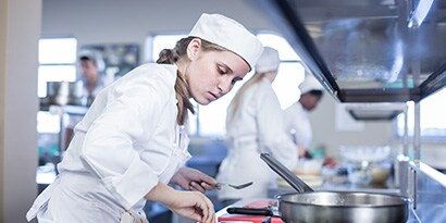 A chef works over a food preparation area in a commercial kitchen.

