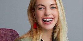 Female dental patient smiling in chair showing 3M™ Clarity™ Advanced ceramic braces.
