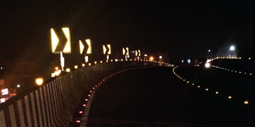 A highway at night with yellow signs.
