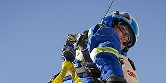 Worker hanging in sky in safety harness wearing anti fog safety glasses
