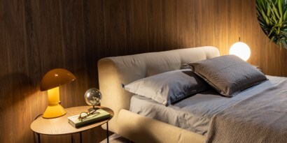 A bed with pillows and a lamp on a table
