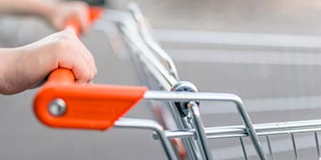 A person pushing a grocery cart that has been wiped with 3M Instant Microbe Removing Wipes.
