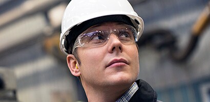 A person wearing a white hard hat and goggles
