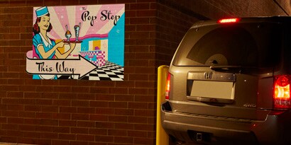 A wall graphic showing the direction of a Pop Stop store shining at night using 3M reflective films.
