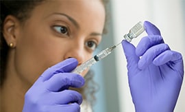 Female scientist drawing liquid from a vial with a syringe