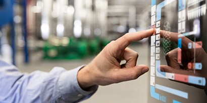 Image of a man interacting with a touch screen interface in an industrial plant.
