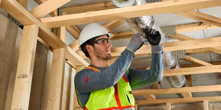 Image of a worker among ceiling joists installing 3M™ Fire Barrier Dryer Ventilation Wrap
