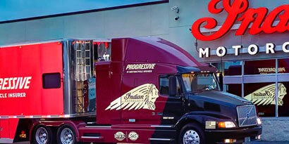 Indian motorcycles truck wrapped in reflective film in front of illuminated storefront signage
