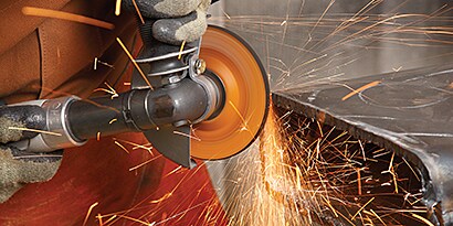 Hand holding angle grinder demonstrating beveling application
