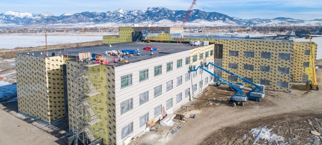 Several buildings wrapped in an air barrier with external cladding nearly completed on one wall