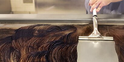 3M Scotch-Brite Quick Clean Griddle Liquid being squeegeed off the griddle with clean
