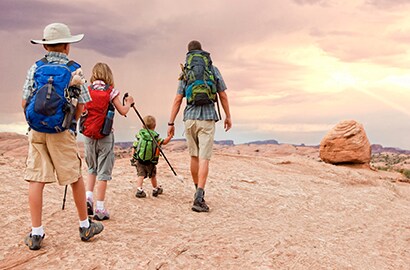 Dad and three kids hike the desert at sunset