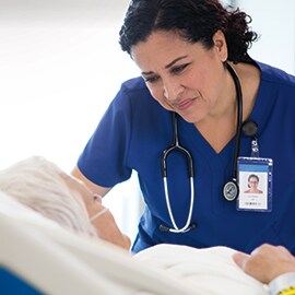 An image of a clinician holding the hand of an elderly patient.