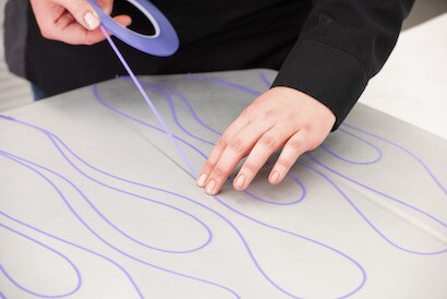 Technician showing how to achieve fine line masking by creating a flame design on a panel.
