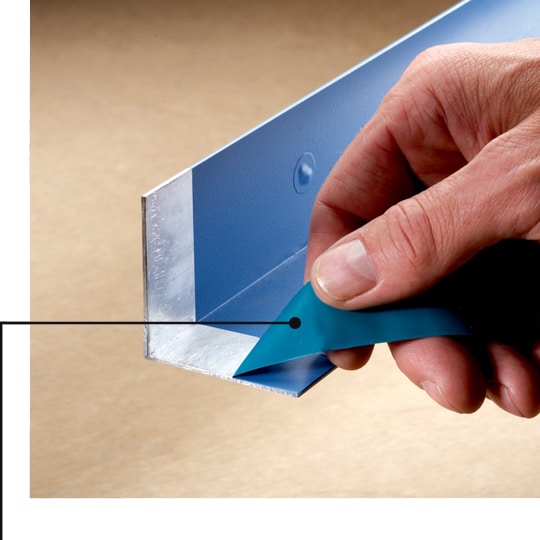Masking tape being removed from L-shaped metal, showing a clean mask line