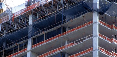 Tall building under construction with guardrails and netting around open floors
