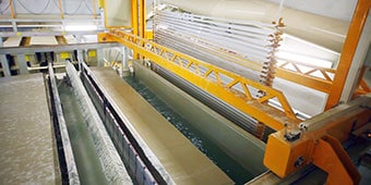 Image of a worker in protective gear applying powder coat paint to metal parts
