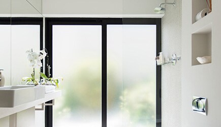 The windows in a brightly lit room have a decorative window film, adding beauty while enhancing privacy.