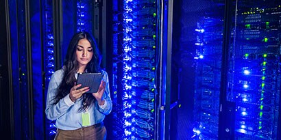 Applicable Market Alt Text Data Center: Female technician using a digital tablet while standing next to a server rack
