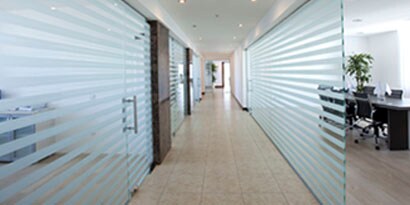 An office hallway with glass walls has striped wall wraps that provide privacy and a sleek look.
