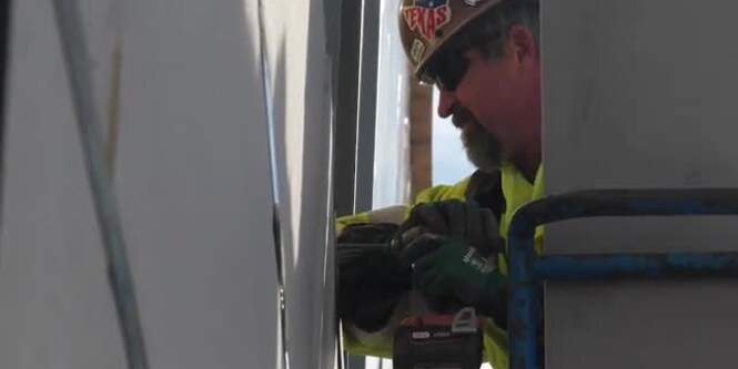 Video still of someone working on a wall

