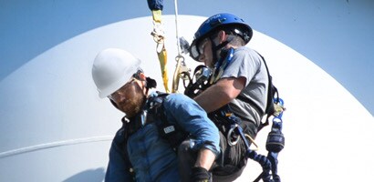 Worker rescuing co-worker at height with controlled ascent device
